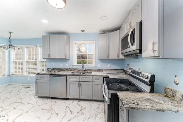a kitchen with stainless steel appliances granite countertop a stove a sink and a microwave