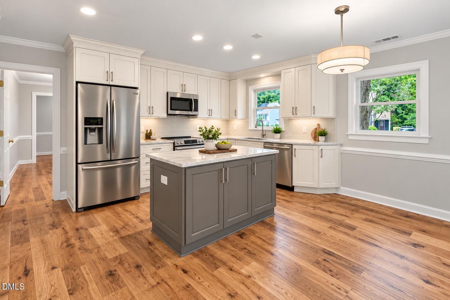 4907 Fortunes Ridge Drive Durham, NC 27713 - Photo 26 of 59 This Virtually Created image shows the kitchen cabinets painted white with a gray island and new cabinet doors, new backsplash, range and microwave and a new LVP flooring throughout the main level.