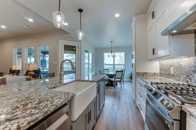 a kitchen with stainless steel appliances granite countertop a stove oven a dining table and chairs with wooden floor