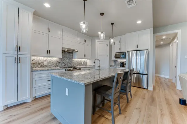 a kitchen with stainless steel appliances granite countertop a table chairs refrigerator and microwave