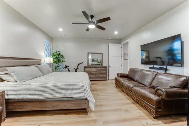 a bedroom with a large bed a couches and a flat screen tv