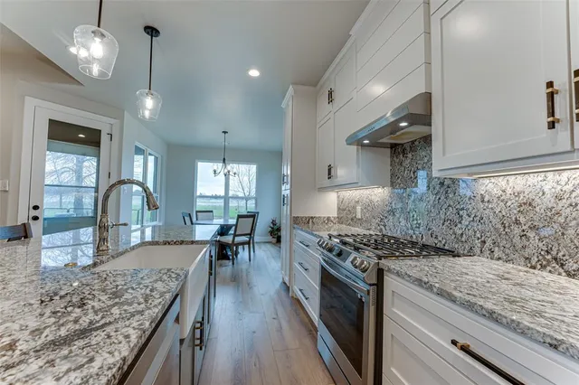 a kitchen with stainless steel appliances granite countertop a lot of counter space and wooden floors