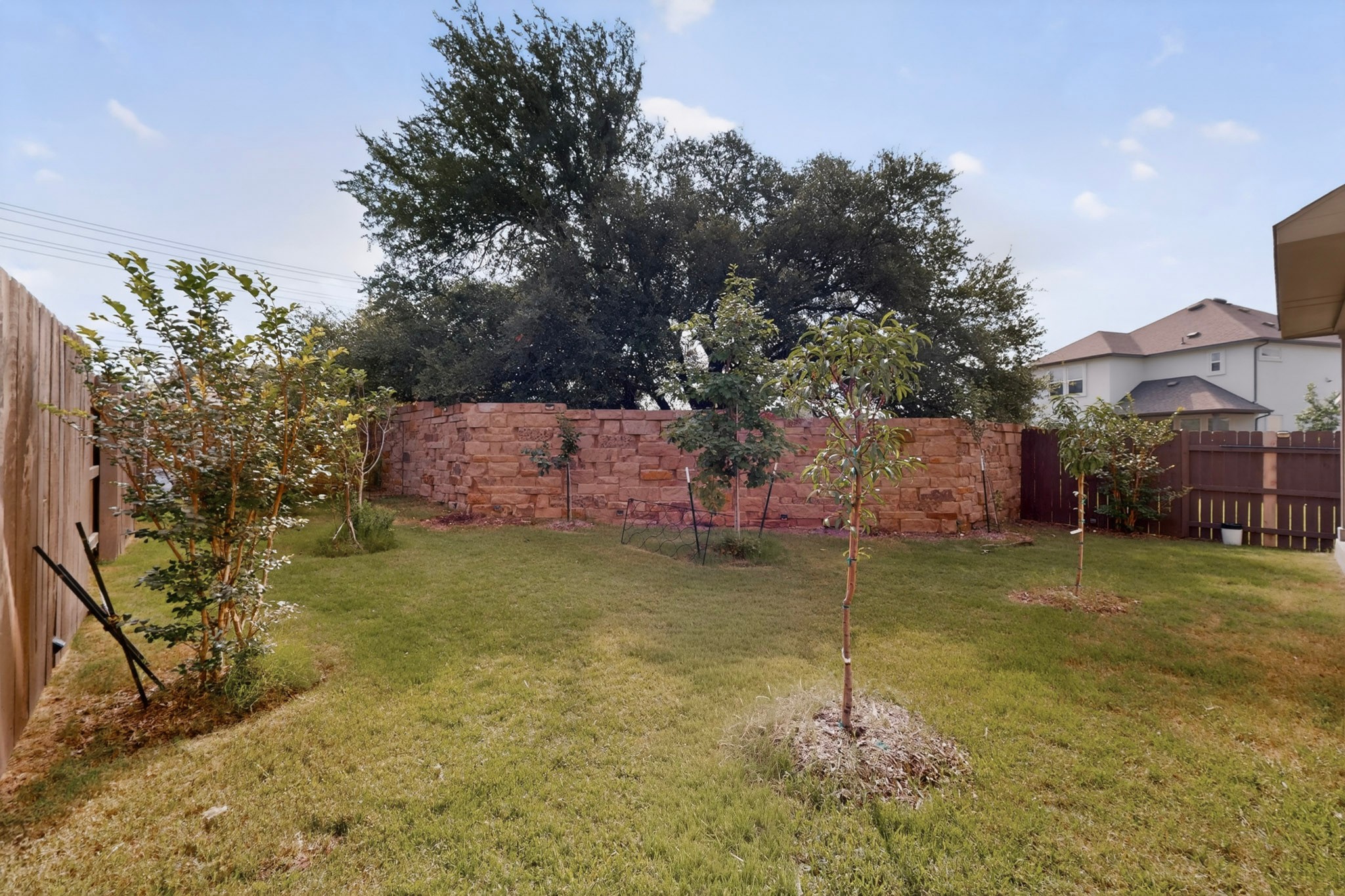 2605 Sam Bass Road, Unit 9 Round Rock, TX 78681 - Photo 36 of 38 A spacious yard with mature trees and a beautiful stone retaining wall.