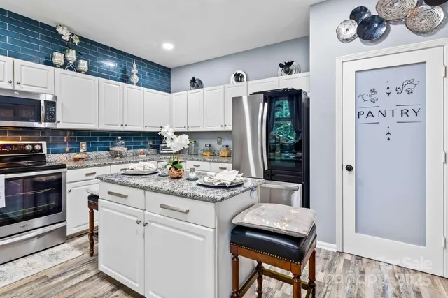 a kitchen with stainless steel appliances granite countertop a stove a refrigerator and a cabinets