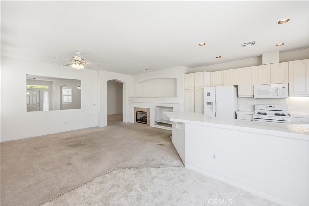 1961 Riviera Avenue Banning, CA 92220 - Photo 30 of 60 a large white kitchen with granite countertop a stove a sink dishwasher and a refrigerator with wooden floor
