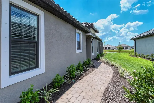 a view of a house with a big yard plants and large tree