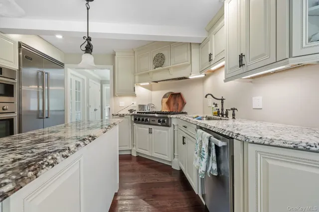 a kitchen with granite countertop a sink stainless steel appliances and cabinets