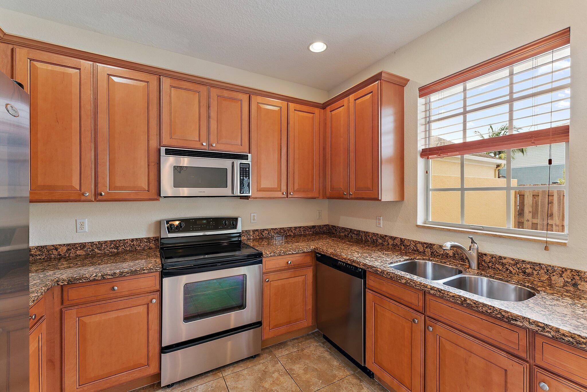 128 West Thatch Palm Circle Jupiter, FL 33458 - Photo 10 of 31 a kitchen with granite countertop stainless steel appliances a sink stove and cabinets
