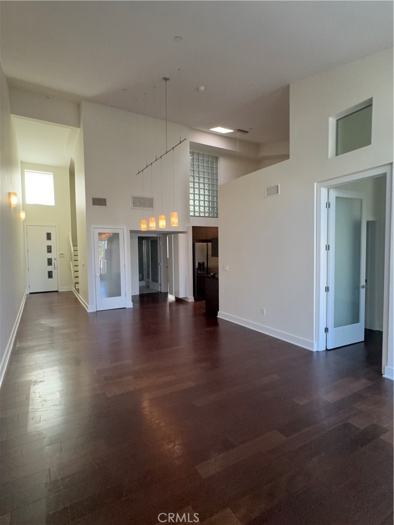 600 Ridgeley Drive Los Angeles, CA 90036 - Photo 4 of 29 an empty room with wooden floor and a kitchen