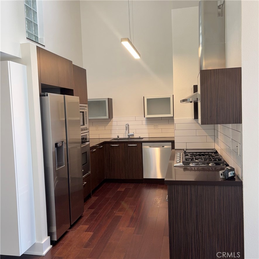 600 Ridgeley Drive Los Angeles, CA 90036 - Photo 5 of 29 a kitchen with stainless steel appliances a refrigerator a sink a stove a microwave and wooden floor