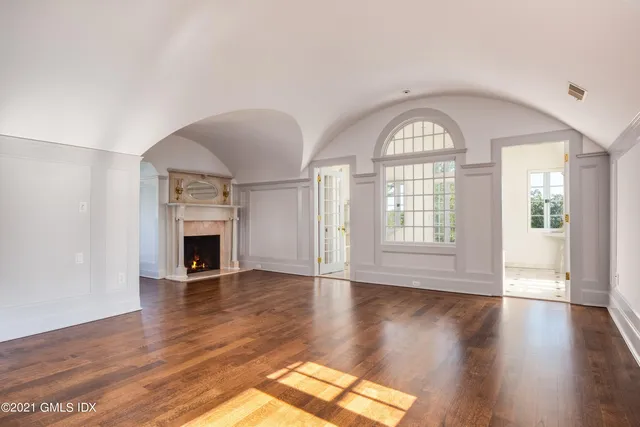 a view of an empty room with wooden floor fireplace and a window