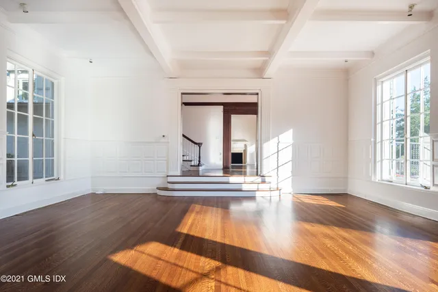 a view of an empty room with wooden floor fireplace and a window