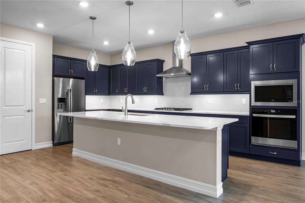 4474 Northwest 53rd Avenue Road Ocala, FL 34480 - Photo 13 of 78 a large kitchen with stainless steel appliances kitchen island granite countertop a stove a refrigerator and a large countertops with wooden floor