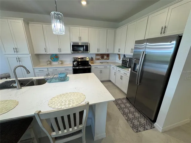 a kitchen with white cabinets a sink a stove a refrigerator and cabinets