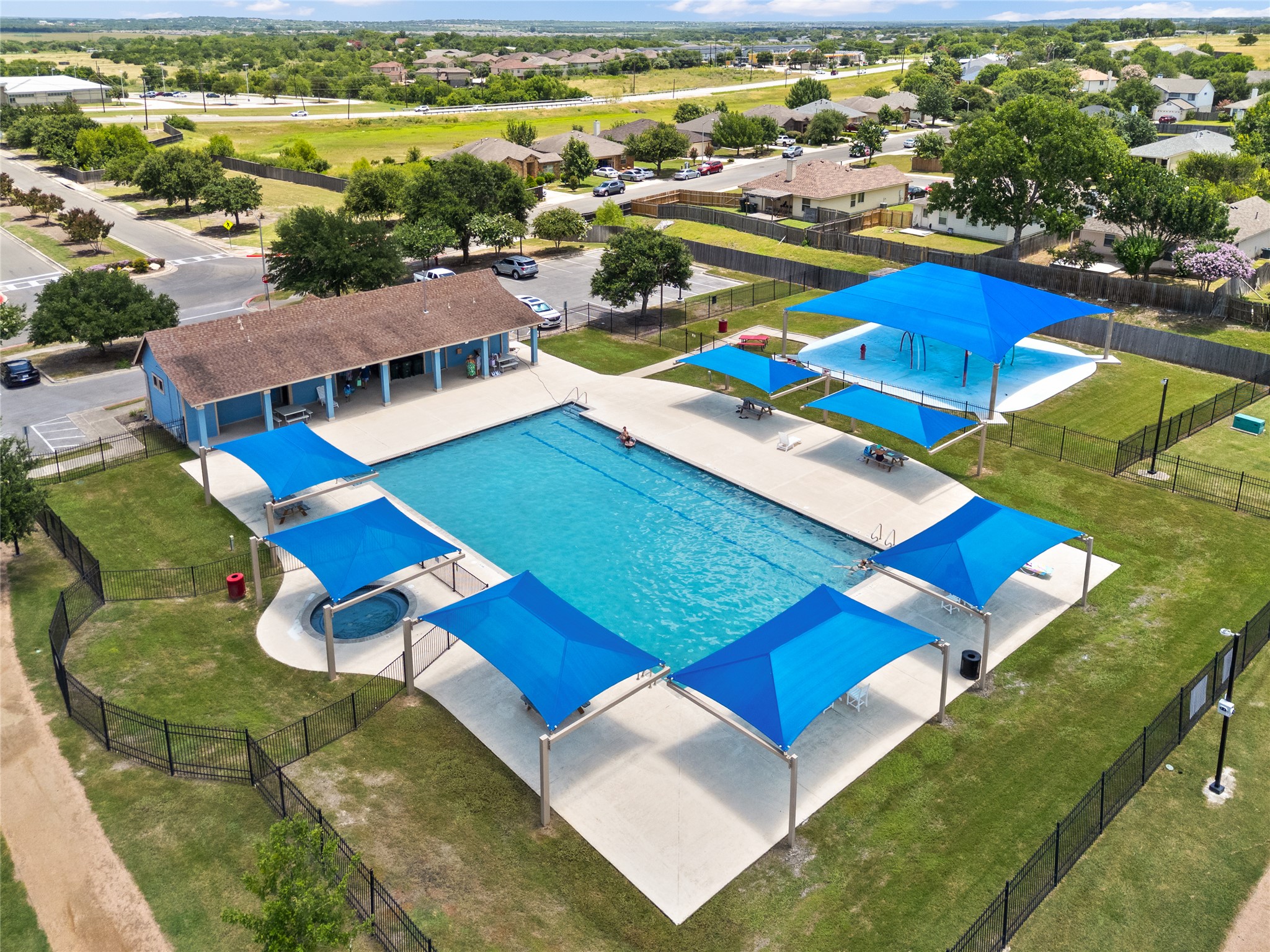 256 Alpha Kyle, TX 78640 - Photo 25 of 27 An aerial perspective reveals the vibrant community pool and clubhouse, nestled amongst green lawns and residential surroundings.