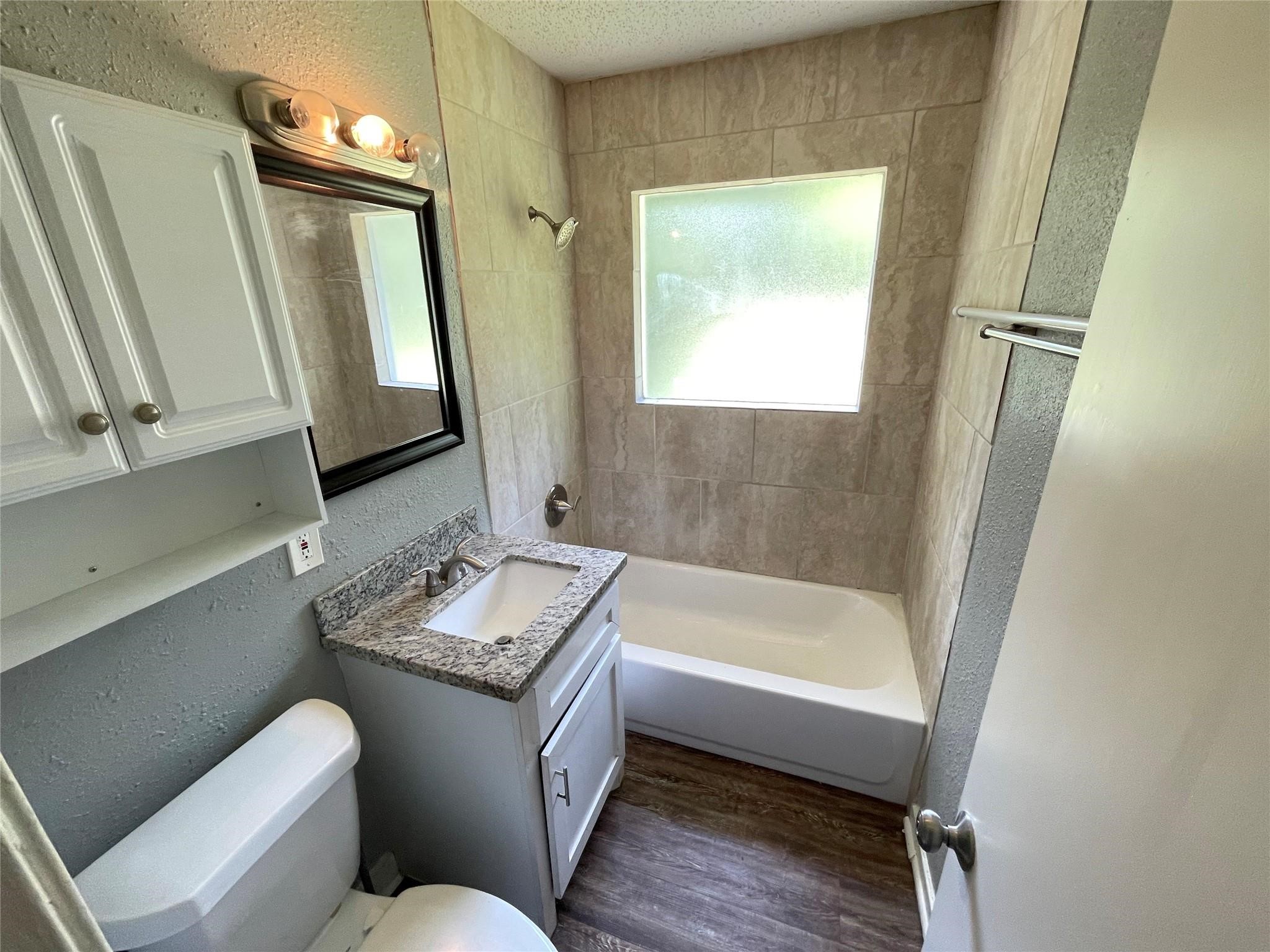 5213 Anzio Road Houston, TX 77033 - Photo 15 of 20 a bathroom with a granite countertop sink toilet a mirror and bathtub