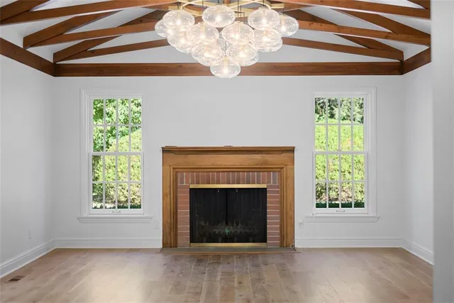 a view of an empty room with wooden floor a fireplace and a window
