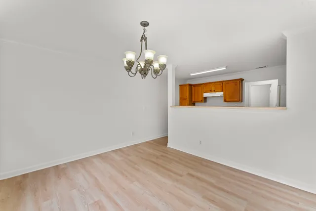 a view of a livingroom with a chandelier fireplace and wooden floor