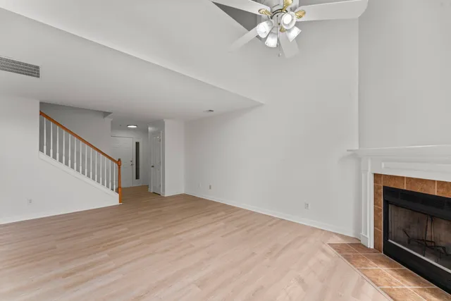 a view of an empty room with wooden floor and a fireplace