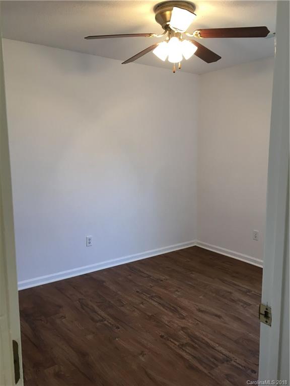 4306 Lothar Ridge Lane Charlotte, NC 28216 - Photo 14 of 22 an empty room with a chandelier fan and wooden floor