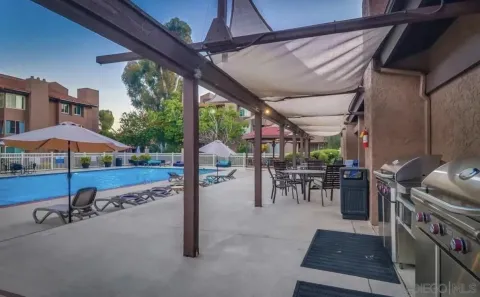 a view of a patio with a table chairs and a barbeque