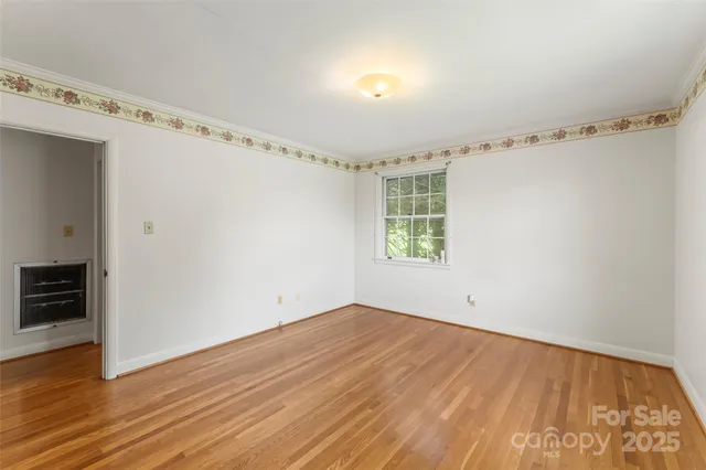 an empty room with wooden floor cabinet and windows