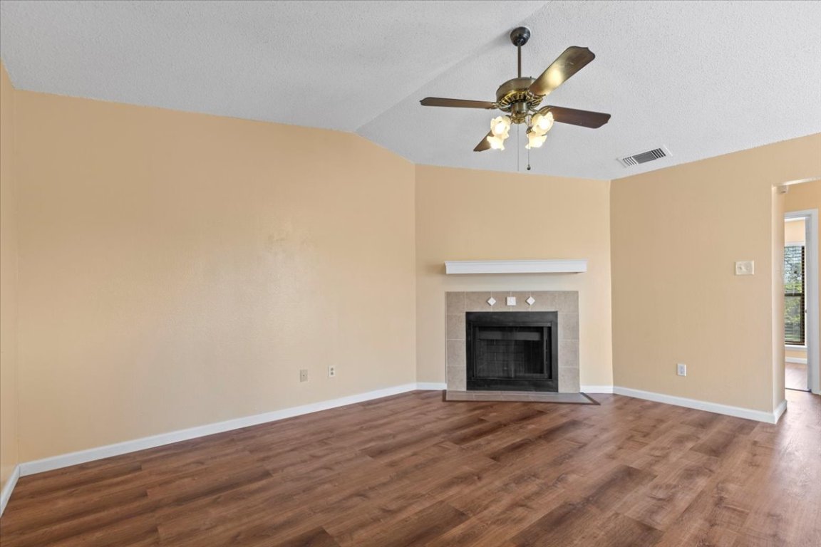10616 Mellow Meadow Drive, Unit 21C Austin, TX 78750 - Photo 12 of 39 an empty room with wooden floor fireplace and fan