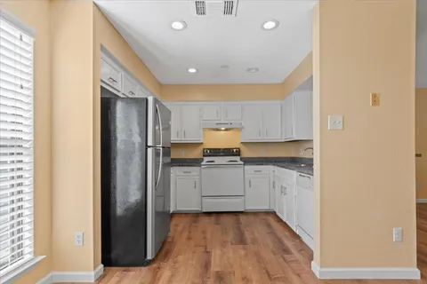 a kitchen with granite countertop white cabinets and white appliances