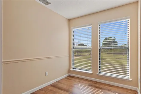 a view of an empty room with wooden floor and a bathroom