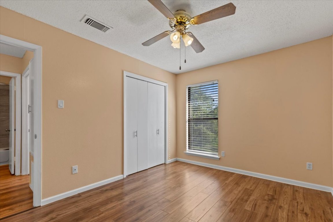10616 Mellow Meadow Drive, Unit 21C Austin, TX 78750 - Photo 21 of 39 an empty room with wooden floor chandelier fan and windows