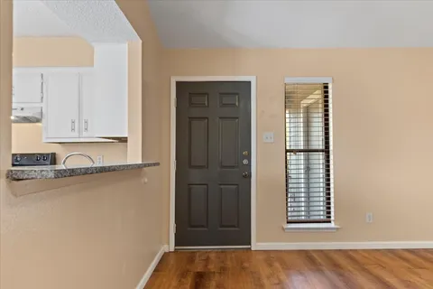 a view of an empty room with wooden floor fireplace and a window
