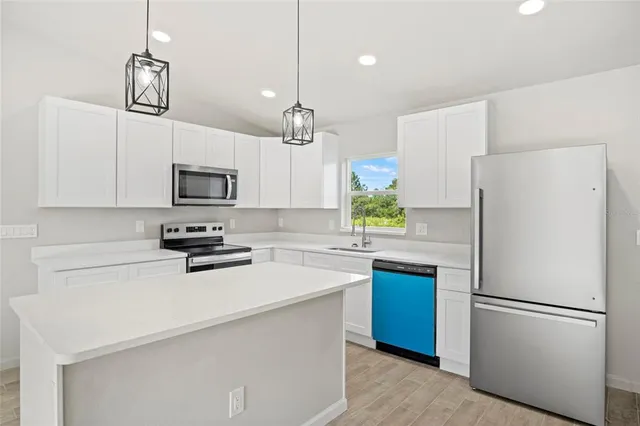 a kitchen with a refrigerator a stove a microwave and white cabinets