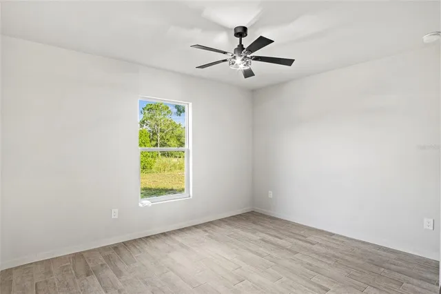 an empty room with window and ceiling fan