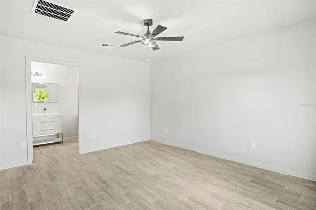 a view of empty room with wooden floor and ceiling fan