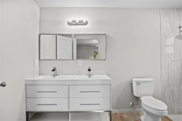 a bathroom with a toilet a sink a mirror and a shower