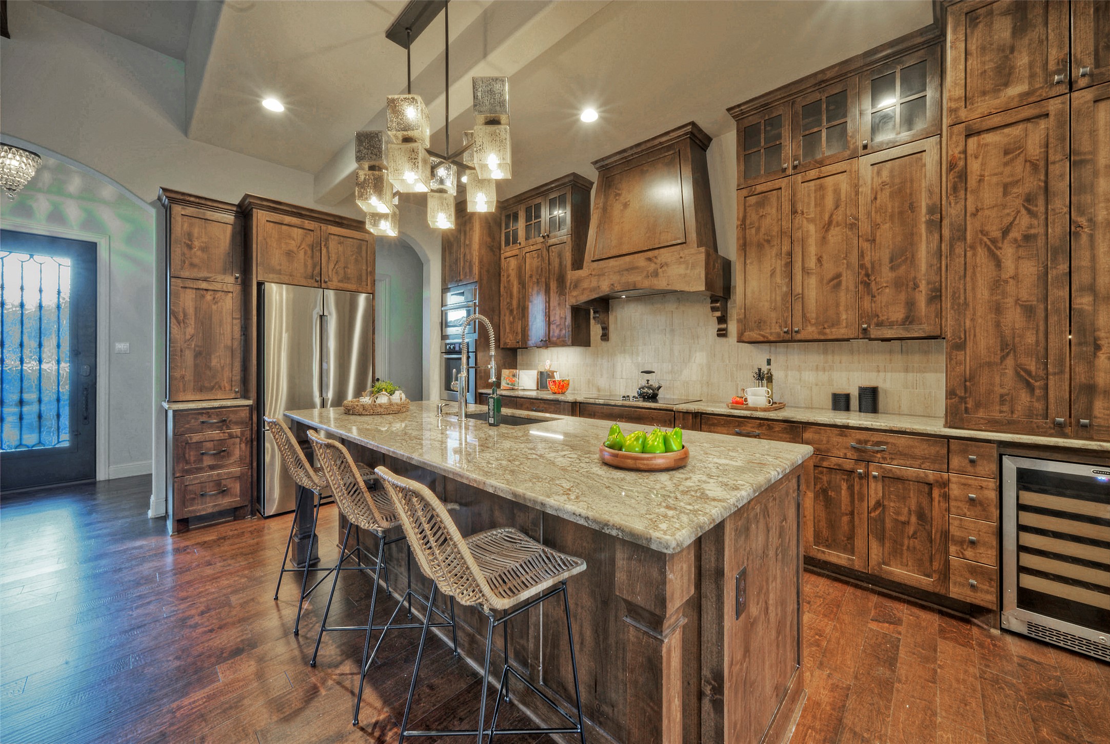 7 Parkside Road The Hills, TX 78738 - Photo 10 of 36 Kitchen with beverage cooler, a kitchen bar, dark wood finished floors, light stone counters, and stainless steel refrigerator