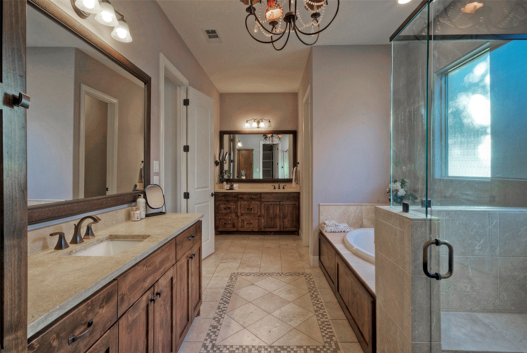 7 Parkside Road The Hills, TX 78738 - Photo 17 of 36 Full bathroom featuring two vanities, a stall shower, inlaid floor details, a garden tub, and a chandelier