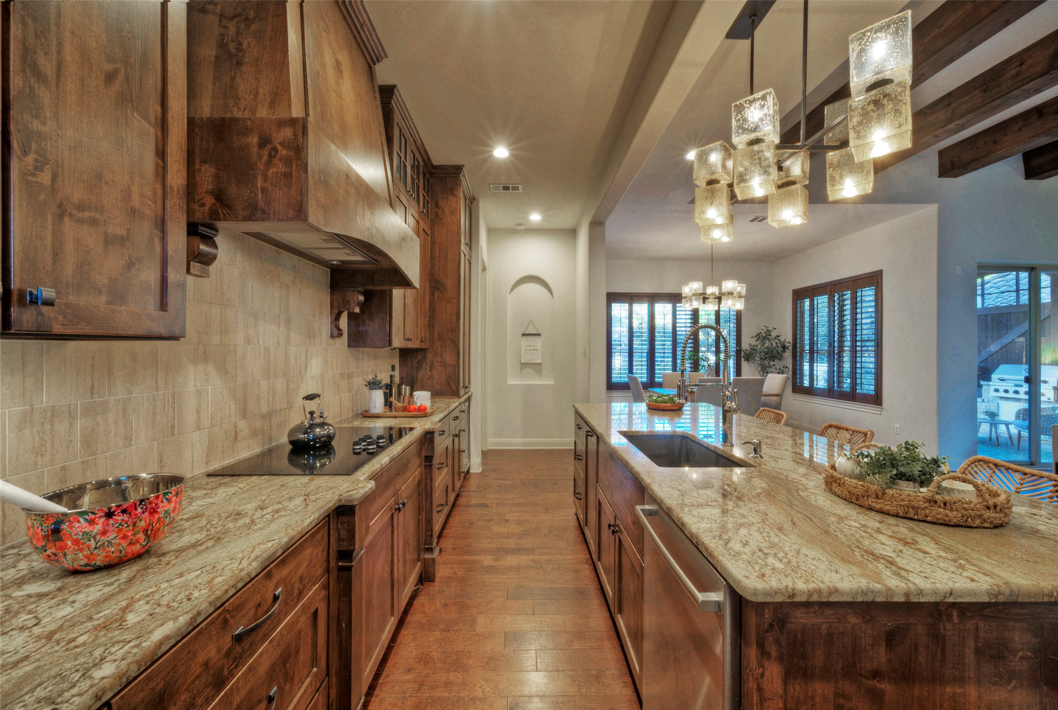 7 Parkside Road The Hills, TX 78738 - Photo 9 of 36 Kitchen with light stone counters, a large island, stainless steel dishwasher, a chandelier, and dark wood-style floors