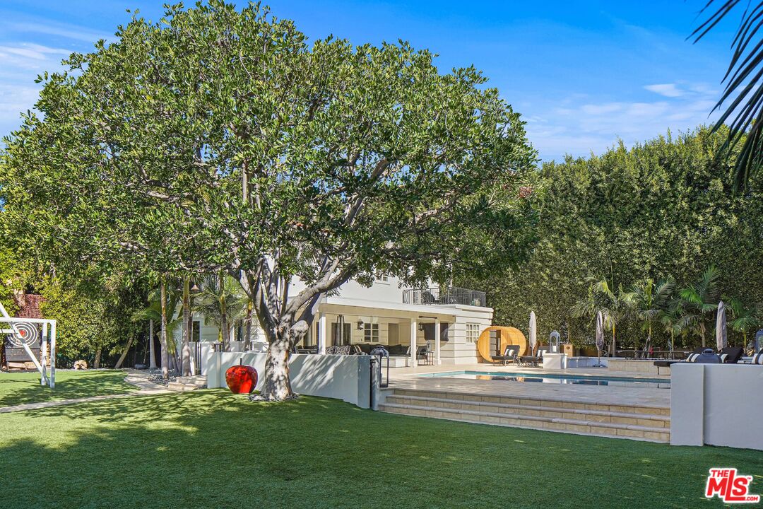 708 North Hillcrest Road Beverly Hills, CA 90210 - Photo 7 of 11 a front view of a house with garden and trees