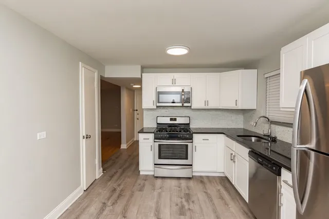 a kitchen with a refrigerator stove and white cabinets