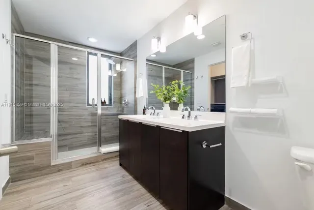 a bathroom with a double vanity sink mirror and shower