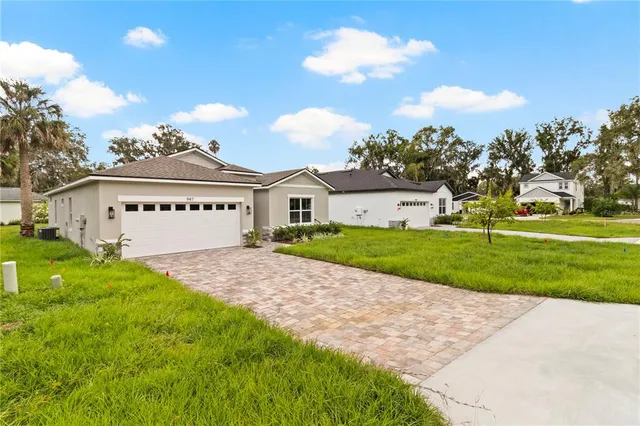 a view of a white house with a big yard and large trees