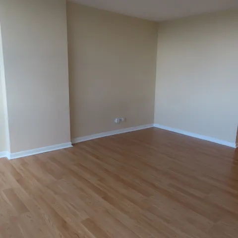 a view of a hallway to an empty room with wooden floor and staircase