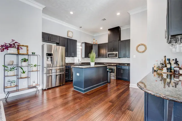 a kitchen with stainless steel appliances kitchen island granite countertop a refrigerator and a stove top oven