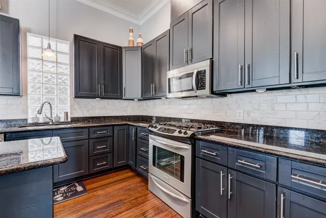 a kitchen with stainless steel appliances granite countertop wooden cabinets stove top oven and sink