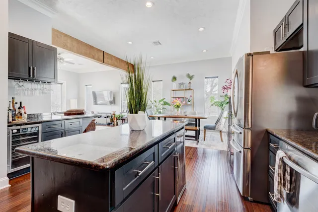 a kitchen with granite countertop a refrigerator a stove a sink a dining table and chairs with wooden floor