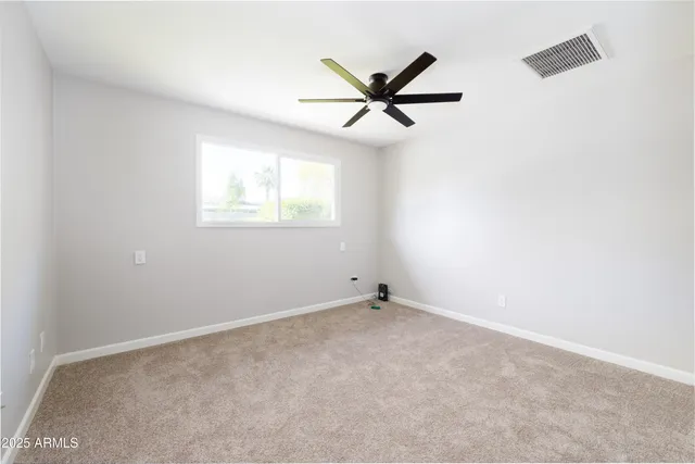 an empty room with a window and a fan