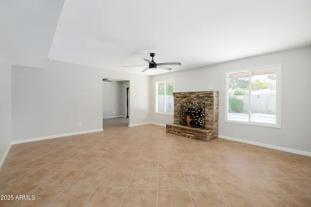 an empty room with windows and fireplace