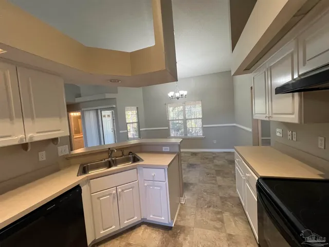 a large kitchen with granite countertop a sink and dishwasher a stove top oven with wooden floor