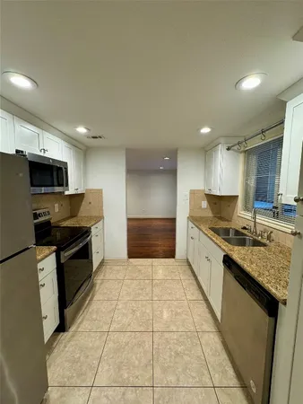 a large kitchen with a large counter top stainless steel appliances and cabinets